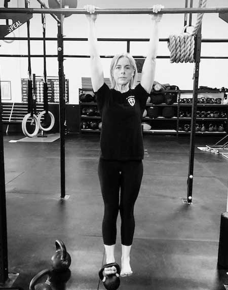 Jen Meehan performing the weighted hollow position on the bar