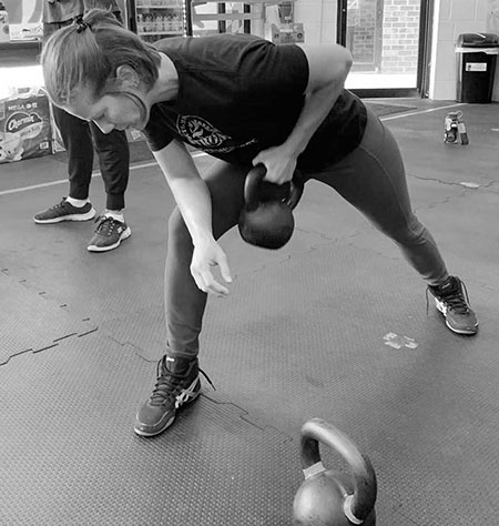 A young woman performing the one-arm kettlebell row