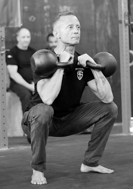 A man performing the double kettlebell front squat